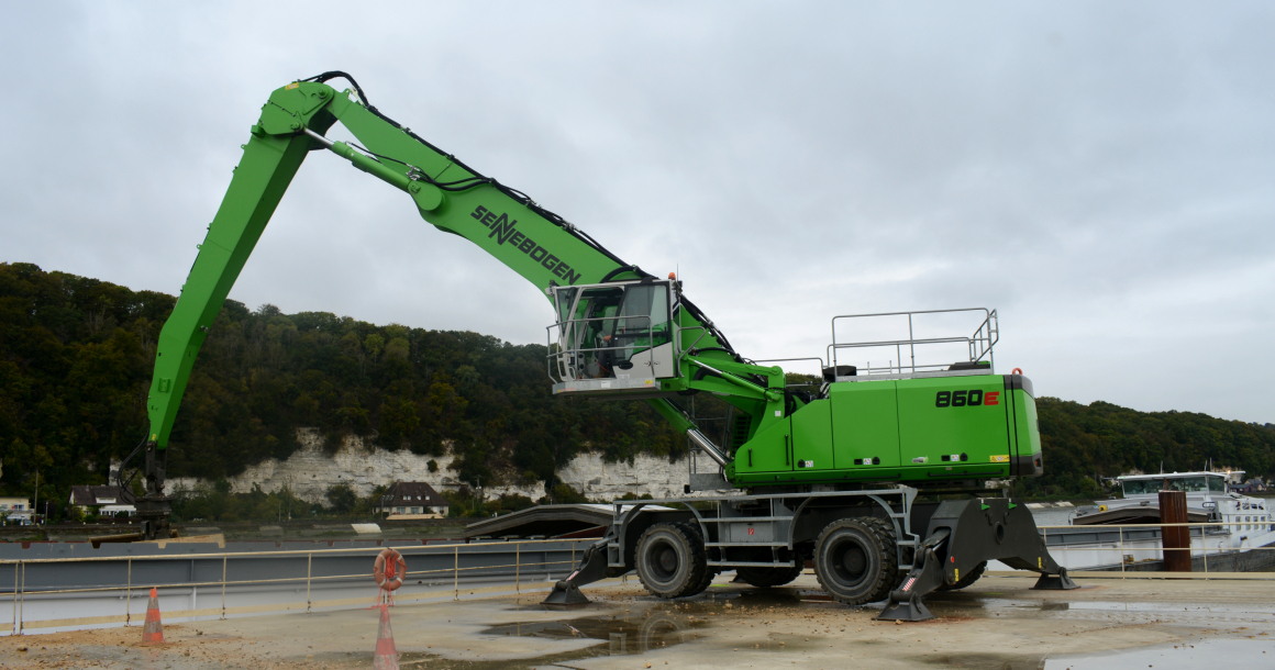 Sur un quai à Anneville-Ambourville, en Seine-Maritime, la pelle Sennebogen 860 E Hybrid de la société F.C.H. décharge des matériaux inertes.